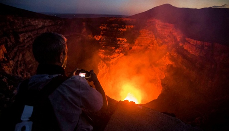 A tourist takes pictures of a lava lake inside the crater of the Masaya Volcano in Masaya, some 30km from Managua on May 19, 2016.