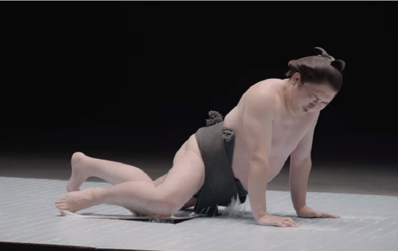 A screen capture of the video shows a sumo wrestler struggling to free himself from the powerful glue used in the cockroach traps.