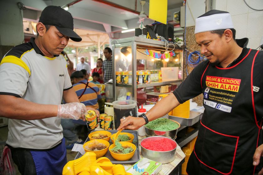 Mohd Hafez Hamed spoons the cendol into the bowls with shaved ice and syrup. 