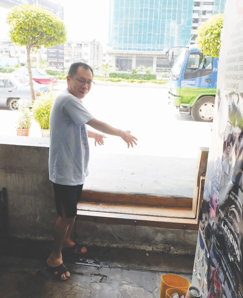 Yap shows how high the water was outside his shop during the floods. u00e2u20acu201d file pic