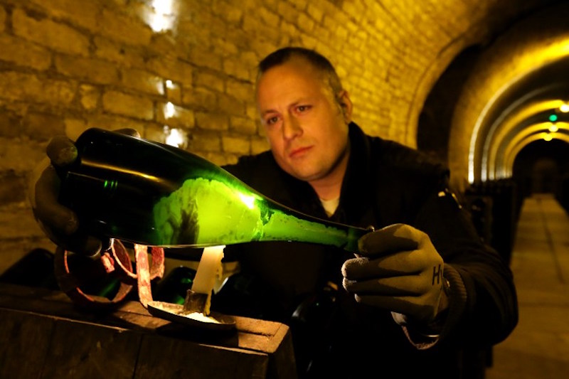 A remueur looks at the dead yeast cells and sediment formed at the bottom a Krug Champagne bottle in the cellar of the Krug Champagne house in Reims, eastern France, April 20, 2016. u00e2u20acu201d AFP pic