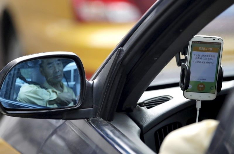 A taxi driver is reflected in a side mirror as he uses the Didi Chuxing car-hailing application in Beijing, China. u00e2u20acu2022 Reuters pic