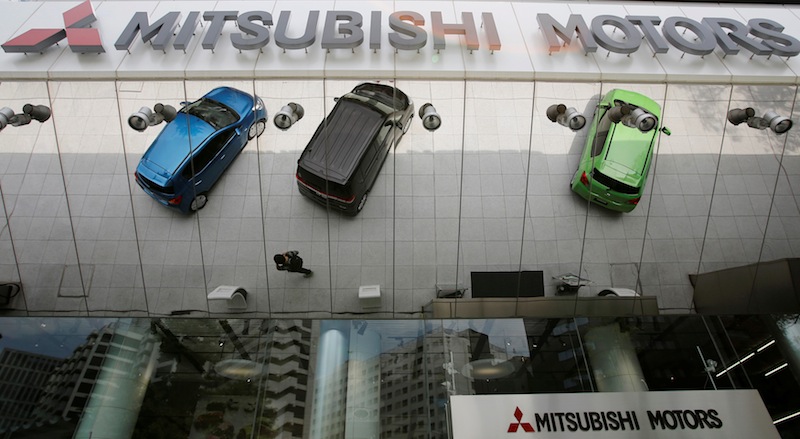 Mitsubishi Motors Corp's vehicles and a passer-by are reflected on an external wall at the company headquarters in Tokyo May 23, 2013. u00e2u20acu201d Reuters pic