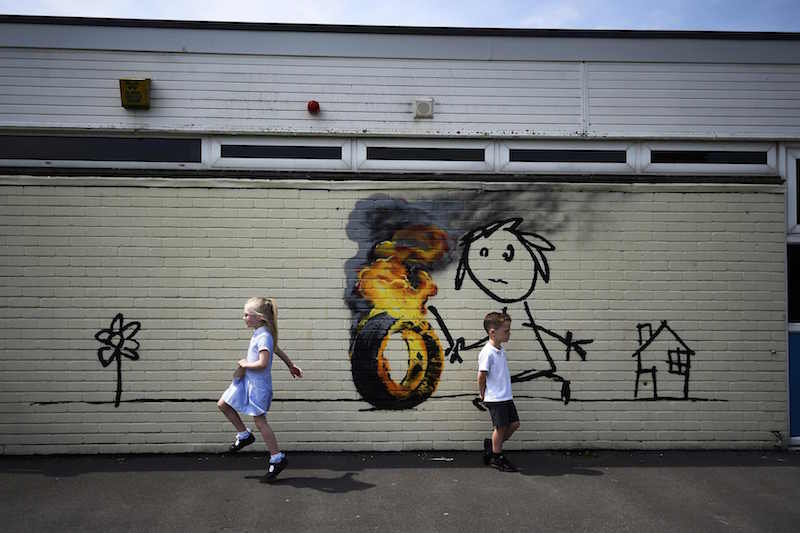 Reception class school children skip past a mural, attributed to graffiti artist Banksy, painted on the outside of a classroom at the Bridge Farm Primary School in Bristol June 6, 2016. u00e2u20acu201d Reuters pic