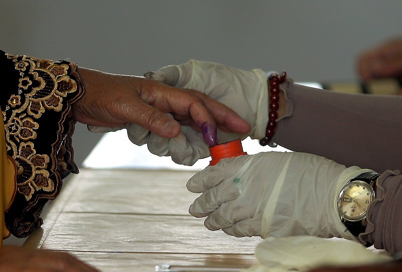 An election commission officer dipping a voteru00e2u20acu2122s finger in the indelible ink at the SMK Raja Muda Musa, which is one of the voting centre under Manong constituency for the Kuala Kangsar by-election, June 18, 2016. u00e2u20acu201d Picture by Farhan Najib Yusoff