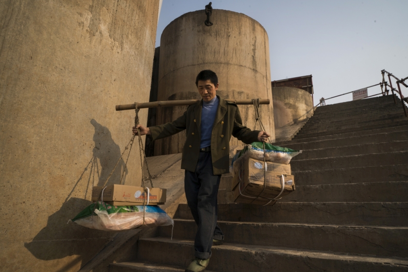 A porter, collectively known as u00e2u20acu02dcbang-bangu00e2u20acu2122, carrying supplies to a passenger boat docked by the Yangtze River in Chongqing, China, April 4, 2016. u00e2u20acu201d Picture by Adam Dean/The New York Times