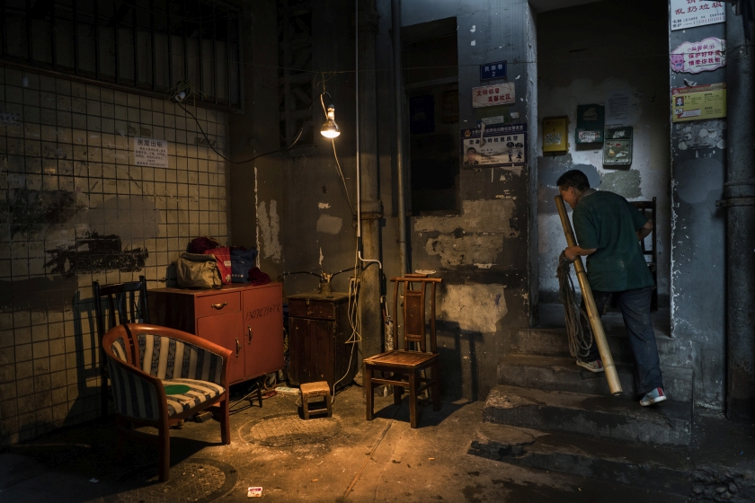 Liao Chengguo, a porter, collectively known as ‘bang-bang’, by the stairwell of the two-bedroom apartment he shares with his wife and daughter and another family in Chongqing, China, April 6, 2016. — Picture by Adam Dean/The New York Times