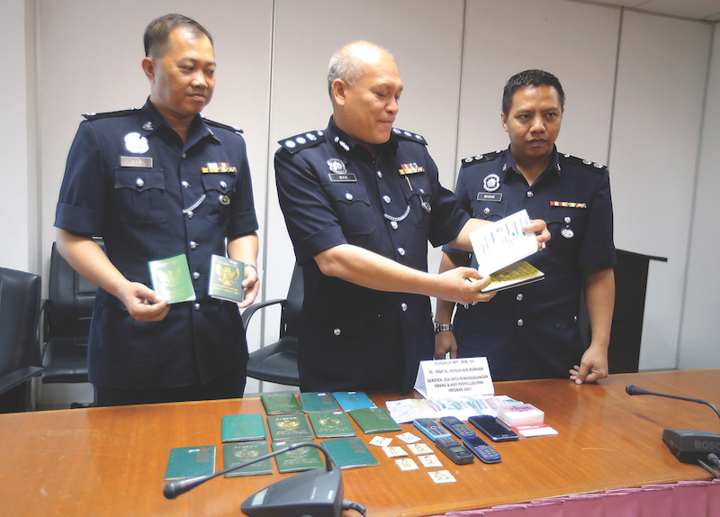 DSP Tey Kong Seng (left) and Insp Al-Ikhsan Borhan show some of the items seized from the migrants. u00e2u20acu201d Picture by Farhan Najib