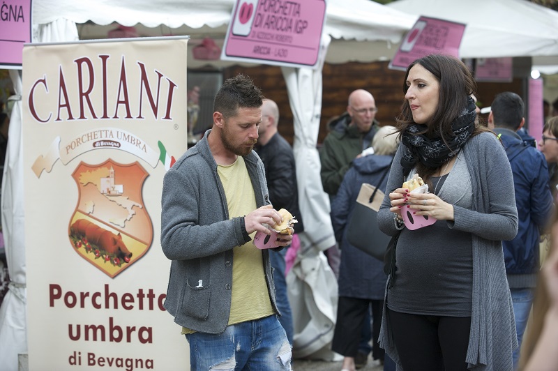 Customers eating sandwiches with porchetta, a whole pig deboned and gutted, then stuffed with garlic and herbs, and roasted in its skin until crunchy and juicy, at a festival in Umbria, Italy, May 15, 2016. — Picture by Chris Warde-Jones/The New York Times