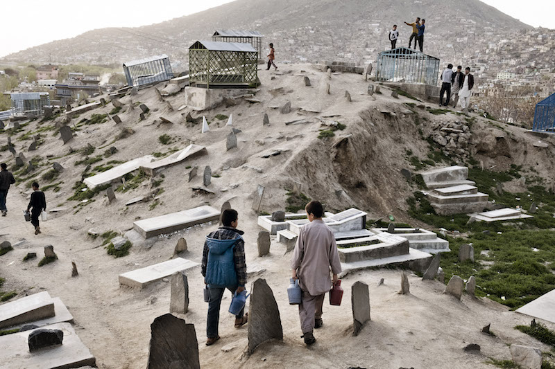 Ajmal, 10, right, and Zikrullah, 14, carry water for sale to wash headstones at Karte-e-Sakhi cemetery, where children hustle for tips, a cotton-candy seller circulates and cockfights are held every weekend, in Kabul, Afghanistan, April 7, 2016. — Picture by Adam Ferguson/The New York Times
