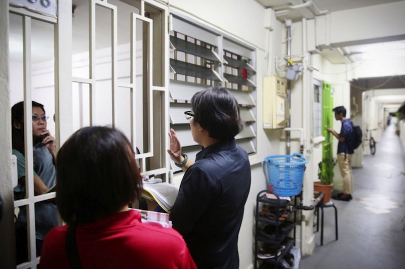 The MOH began informing residents of the affected block yesterday evening, with officers (in black) and members of Ang Mo Kio Town Council making door-to-door visits. u00e2u20acu201d TODAY pic