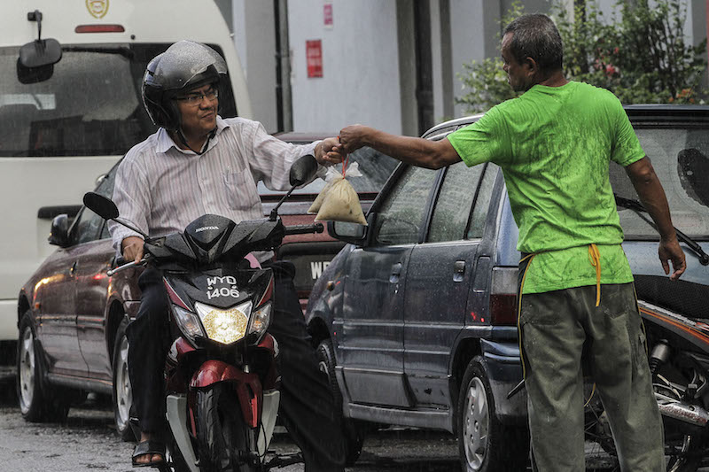 Volunteers distribute the ‘bubur lambuk’ to motorcyclists.