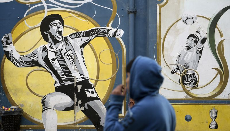 A youngster watches a graffiti depicting Argentine former football star Diego Maradona celebrating a goal (left) and when scoring his famous 'hand od God,' in Buenos Aires June 22, 2016. u00e2u20acu201d AFP pic