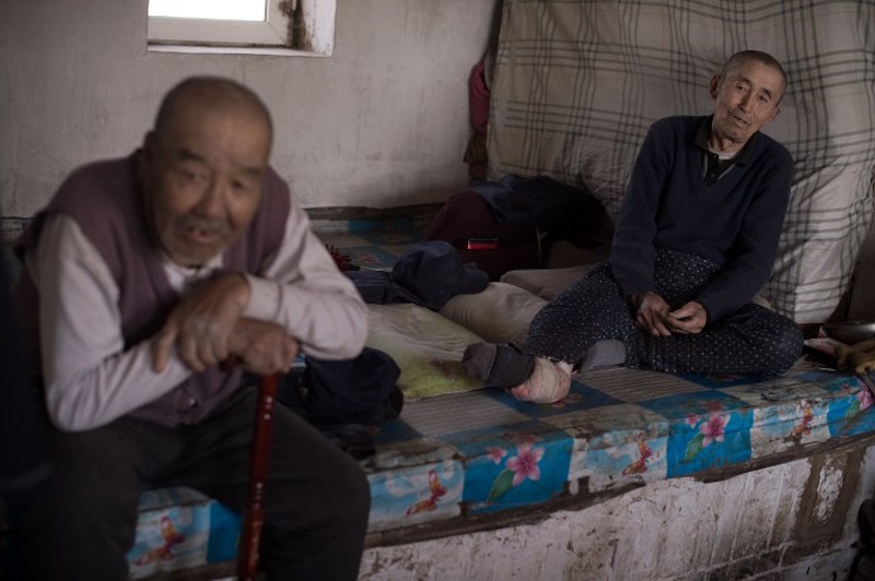 Meng Xianren, 84, sits inside the house of his friend Ji Jinlu (right) in Sanjiazi village, Heilongjiang province, May 4, 2016. — AFP pic
