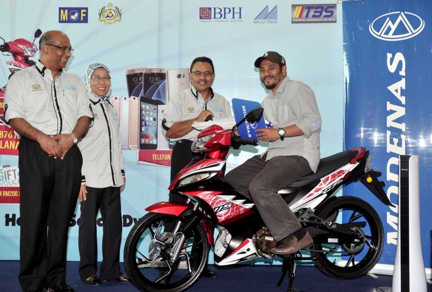 Khazali (third from left) presents a Modenas CT 115S motorcycle to Ahmad Khairul Ishak, who won the u00e2u20acu02dcJom Minta Resit GSTu00e2u20acu2122 contest main prize, at the Integrated Transport Terminal in Bandar Tasik Selatan yesterday. u00e2u20acu201d Picture by Bernama