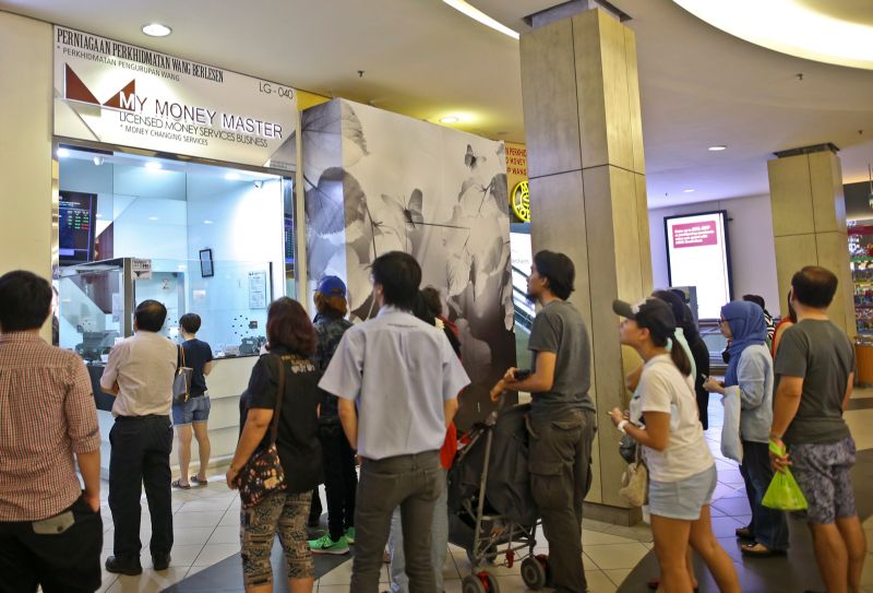 People at a money changer at the Mid Valley Megamall in Kuala Lumpur yesterday. Money changers are reporting brisk business for pounds and euros. u00e2u20acu201d Picture by Azneal Ishak
