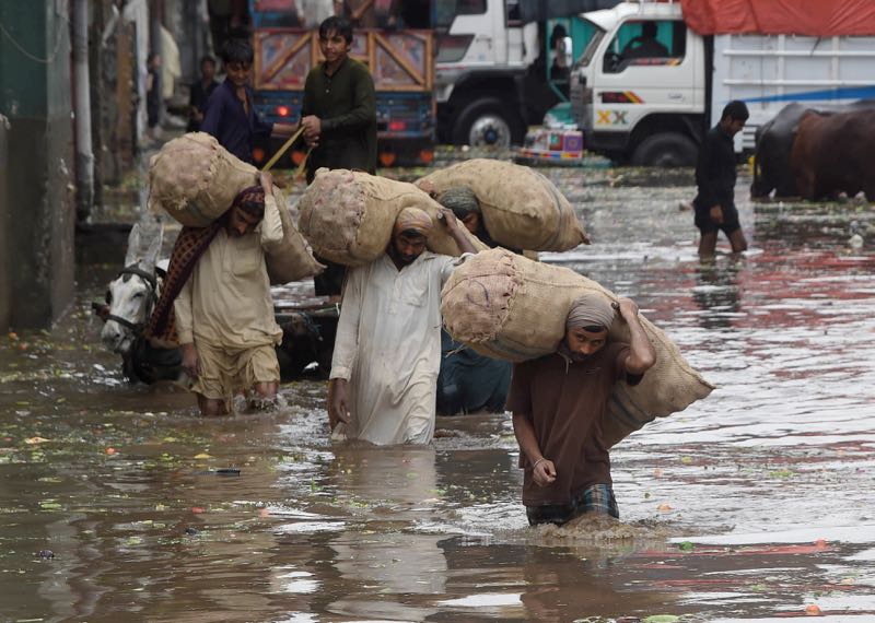 Pakistani labourers carry sacks of onion through floodwaters following heavy rain in Lahore on June 22, 2016. u00e2u20acu201d AFP pic