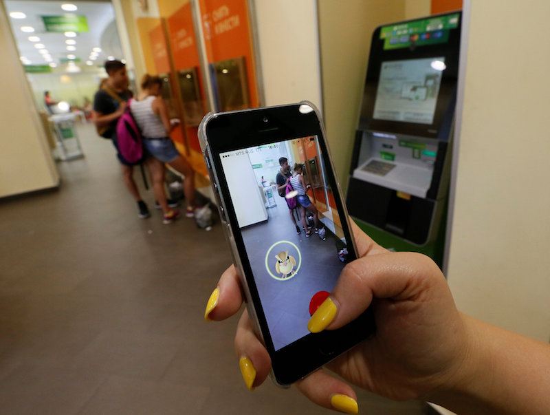 A woman plays the augmented reality mobile game u00e2u20acu02dcPokemon Gou00e2u20acu2122 by Nintendo, as a visitors use an automated teller machine (ATM) at a branch of Sberbank in central Krasnoyarsk, Siberia, July 20, 2016. u00e2u20acu201d Reuters pic
