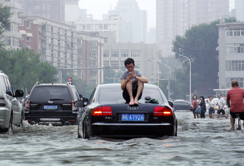 A man sits on top of a car as he is stranded on a flooded street in Tianjin July 20, 2016. u00e2u20acu201d Reuters pic