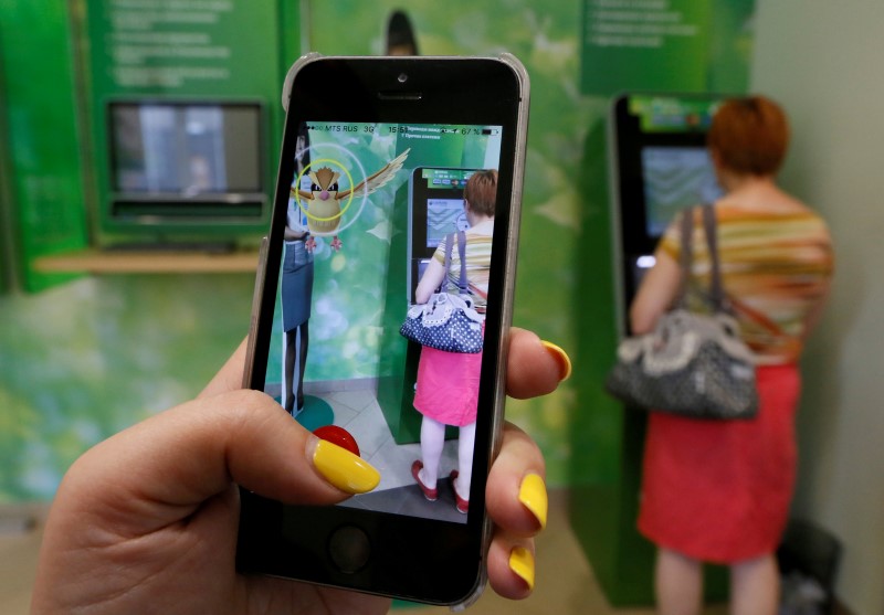 A woman plays the augmented reality mobile game u00e2u20acu02dcPokemon Gou00e2u20acu2122 by Nintendo, as a visitor uses an automated teller machine (ATM) at a branch of Sberbank in central Krasnoyarsk, Siberia, Russia, July 20, 2016. u00e2u20acu201d Reuters pic