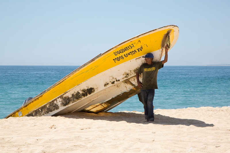 A fisherman stands in the shade under a boat in the small town of Todos Santos, Mexico, July 7, 2016. u00e2u20acu201d Picture by Beth Coller/The New York Times