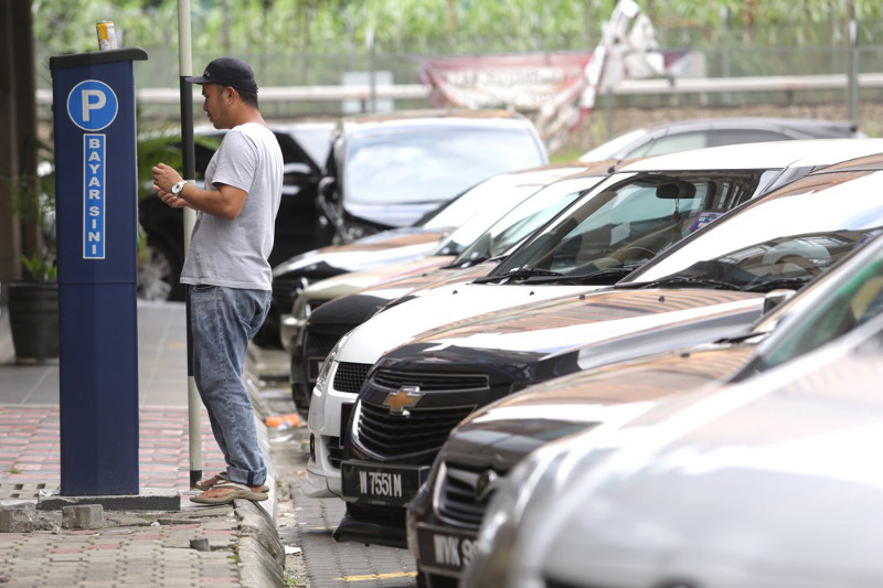 A motorist inserts money into an automated parking fees machine in Kuala Lumpur July 18, 2016. u00e2u20acu201d Picture by Choo Choy May