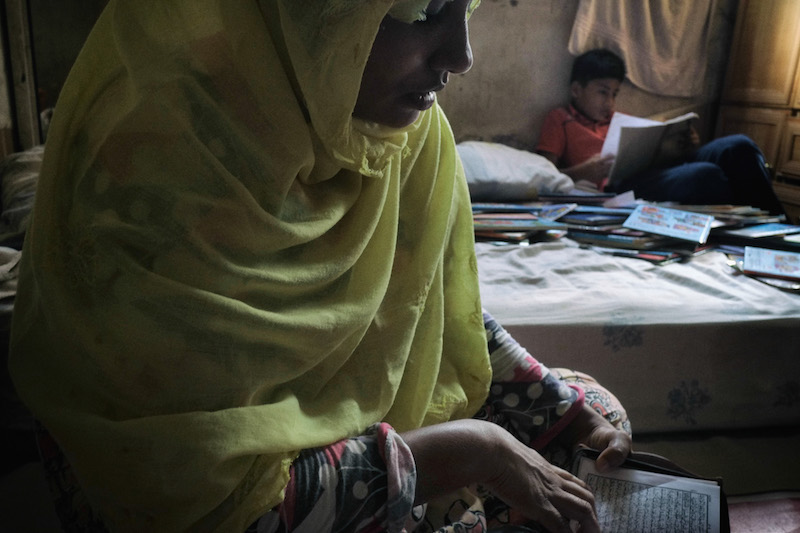 Hasinah Izhar, a Rohingya refugee, reads the Quran as one of her sons studies English homework at their rented room in George Town June 15, 2016. u00e2u20acu201d Picture by Rahman Roslan/The New York Times