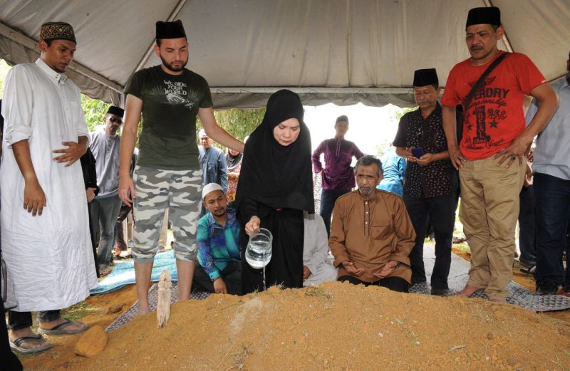 Isteri pelakon veteran Datuk Abdul Aziz Singah menyiram air mawar di pusara allahyarham di Kampung Bongek Acheh, Rembau hari ini. u00e2u20acu201d Foto Bernama