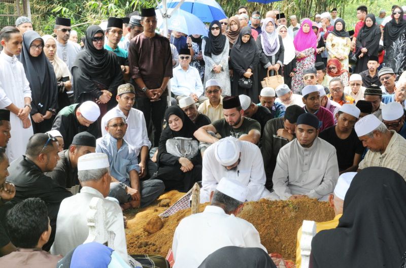 Sebahagian anggota keluarga, sahabat handai dan orang ramai yang menghadiri upacara pengkebumian jenazah Aziz Singah yang disemadikan di sebelah pusara ibunya. — Foto Bernama