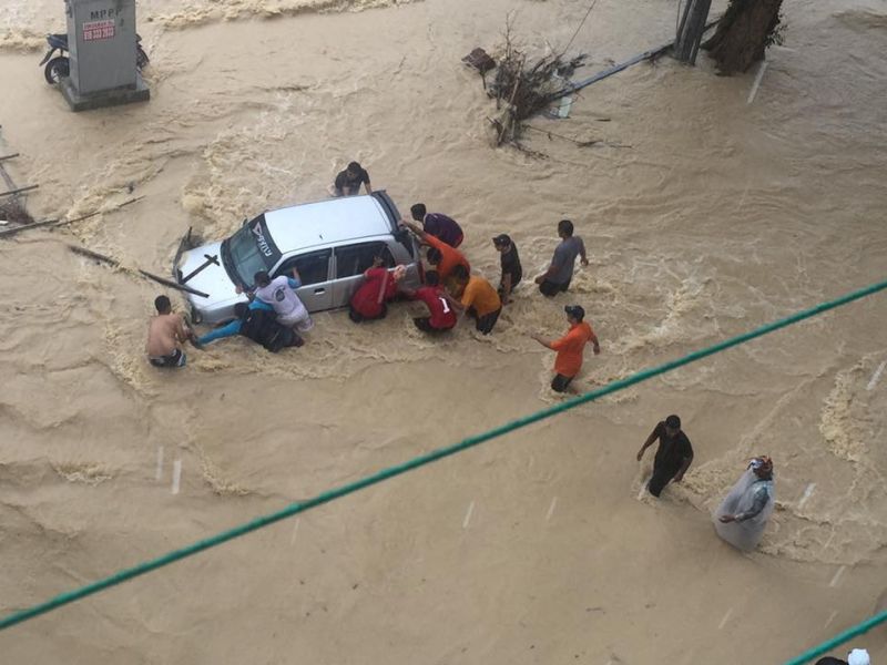 Sekumpulan penduduk di Teluk Bahang menolak sebuah kereta ketika air banjir kilat melanda kawasan tersebut, 18 Julai 2016. u00e2u20acu201d Foto ihsan Facebook Dr Hilmi Yahya 