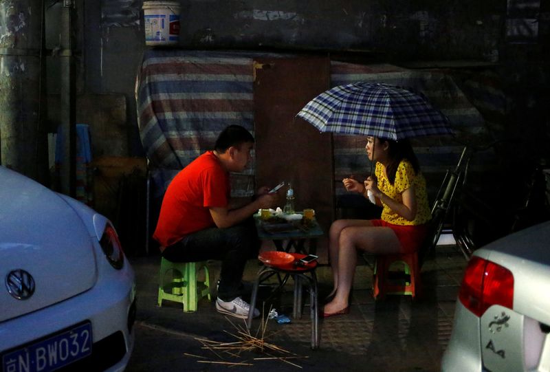 A woman holds an umbrella as she and a man eat at a street restaurant on a rainy night in Beijing July 14, 2016. u00e2u20acu201d Reuters pic
