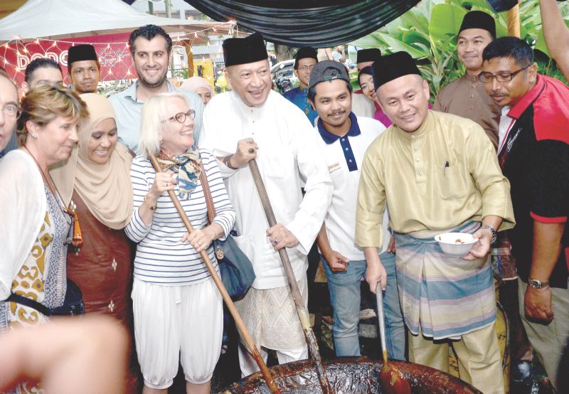 Datuk Seri Mohamed Nazri Aziz (centre) stirring dodol with visitors at the Tourism and Culture Ministry Raya open house at the Malaysia Tourism Centre in Jalan Ampang yesterday. u00e2u20acu201d Picture by Mukhriz Hazim
