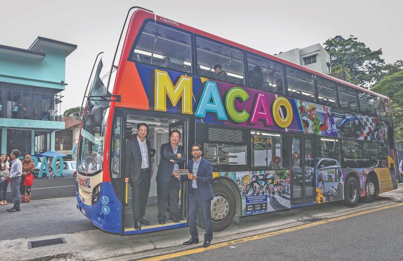 (From left) Quah, Wong and Zahir on a RapidKL double decker bus wrapped in a Macao Tourism advertisement displaying popular tourist attractions. u00e2u20acu201d Picture by Firdaus Latif  