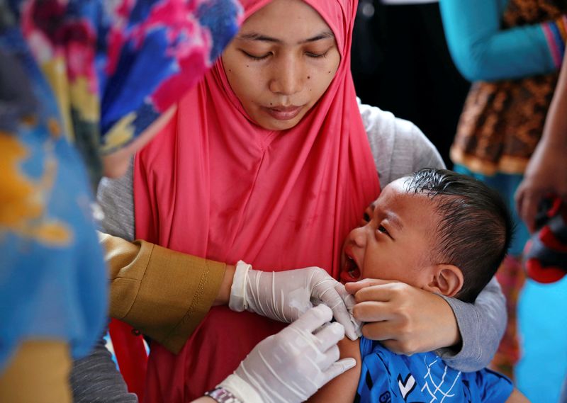 A mother holds her child as he is re-vaccinated by healthcare workers after receiving fake medication from a drug-making ring, at a clinic in East Jakarta July 18, 2016. u00e2u20acu201d Reuters pic