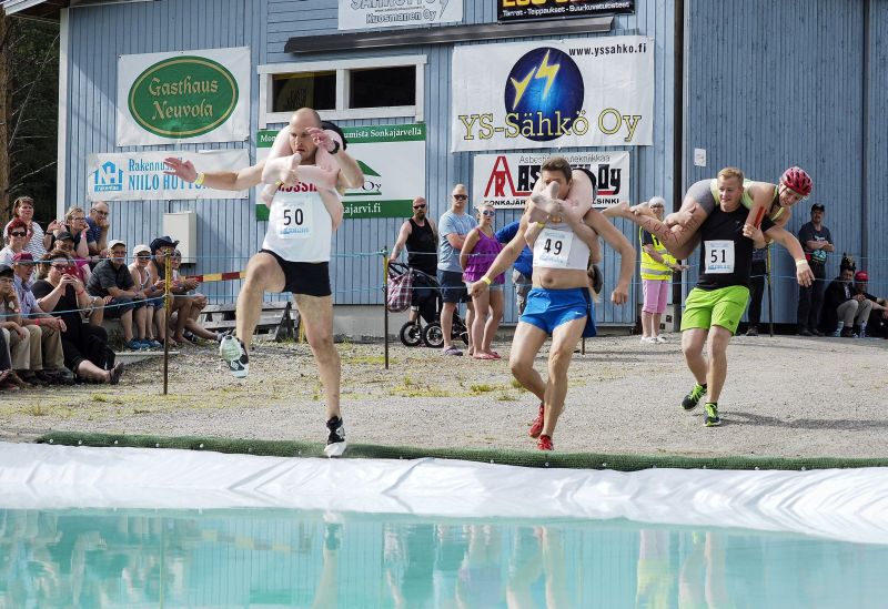Anastasia Loginova/Dimitriy Sagal (L) of Russia, Minna Piippo/Ilpo Haavisto of Finland, Rene Marce Haider/Eva Scharinger of Austria compete, Wife Carrying World Championships, Sonkajarvi, Finland, July 2, 2016. Lehtikuva/Timo Hartikainen/via REUTERS