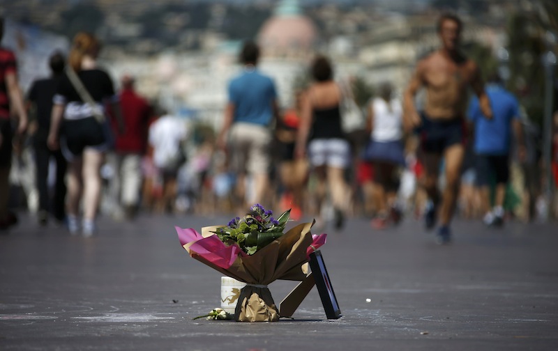 People walk near a bouquet of flowers placed in tribute to victims of the truck attack along the Promenade des Anglais on Bastille Day killing scores and injuring as many in Nice, France, July 17, 2016. u00e2u20acu201d Reuters pic