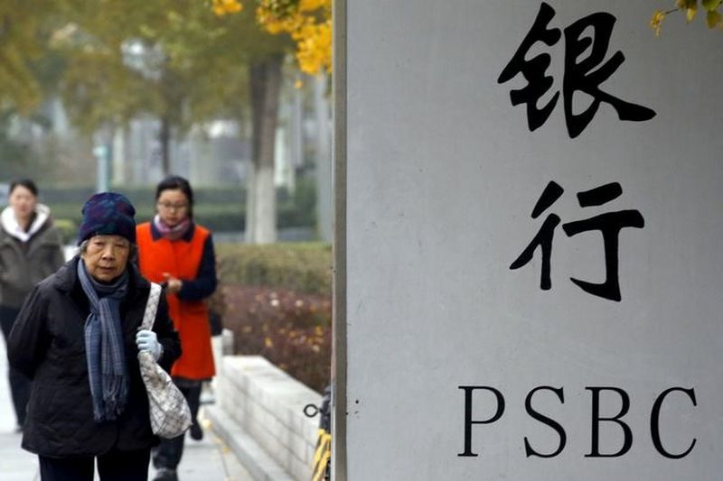 People walk past a sign outside a branch of Postal Savings Bank of China (PSBC) in downtown Beijing November 12, 2015. u00e2u20acu201d Reuters pic