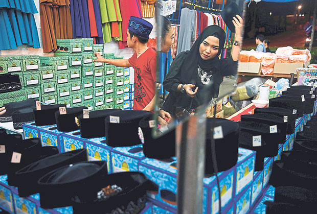 A woman shops for a songkok at a Ramadan bazaar in Singapore on July 4, 2016. — Reuters pic
