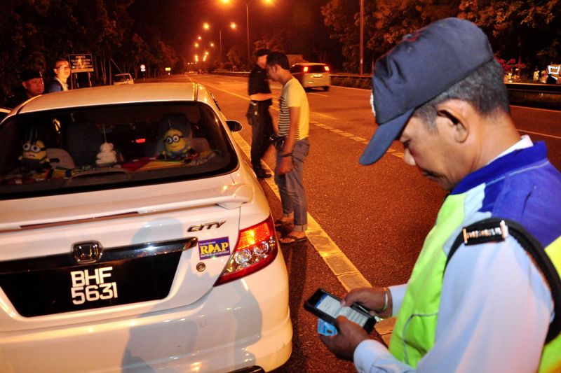 Kelihatan seorang anggota polis trafik sedang menyemak maklumat kenderaan dan pemilik kenderaan menggunakan aplikasi atas talian pada Op Selamat di Jalan Changlun-Kuala Perlis. u00e2u20acu2022 Foto Bernama