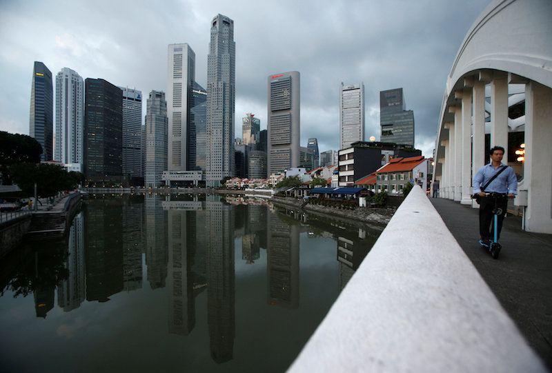 A man passes the skyline of the central business district on a portable scooter in Singapore August 23, 2016. u00e2u20acu201d Reuters pic