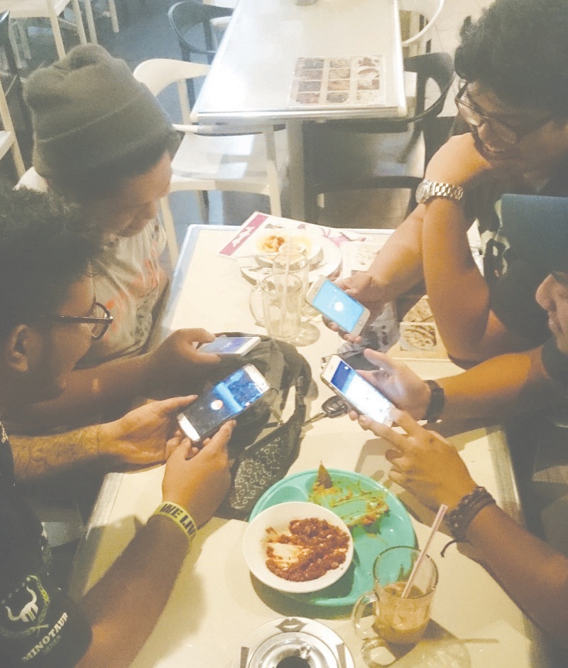 A group of Pokemon Go enthusiasts at a cafe. Playing the game at night and on the road exposes players to accident risks. u00e2u20acu201d Picture by Malay Mail