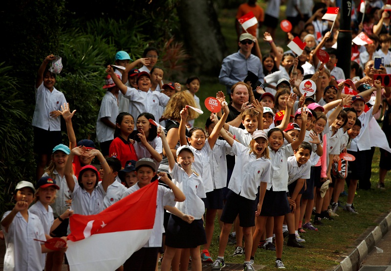 School children wave at Singapore’s Olympic gold medallist swimmer Joseph Schooling during a victory parade on an open top bus in Singapore, August 18, 2016. 