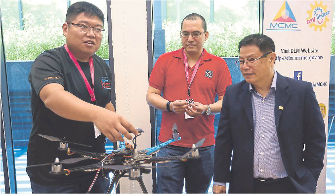 Shee Tze Jin (left) shows a drone built under the myMaker programme as Rizal Aliyuddin (centre) and Tay looks on.