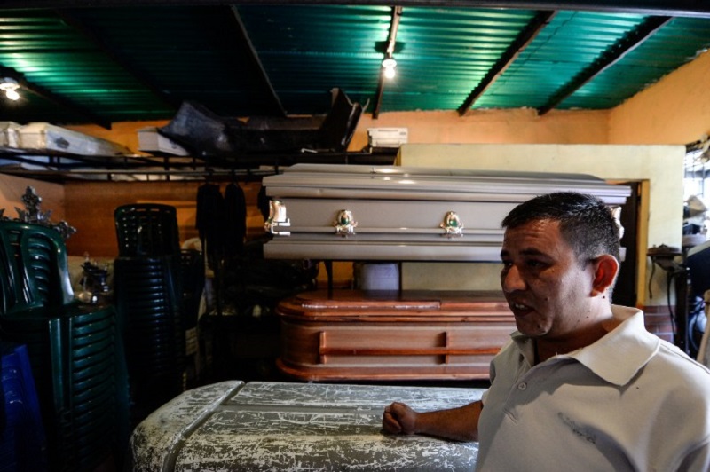 A man stands next to a coffin at the deposit of a funeral parlour at El Valle neighbourhood in Caracas on July 2, 2016. u00e2u20acu201d AFP pic