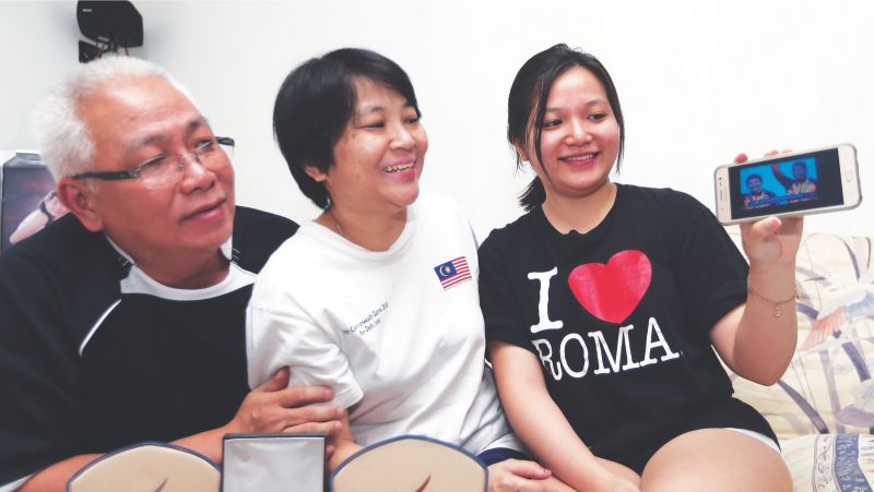 Jun Yeng captures her sisteru00e2u20acu2122s exploits on her mobile phone as Jun Meng and Leow look on happily at their home in Taman Galeri Sukma yesterday. u00e2u20acu201d Pictures by Farhan Najib