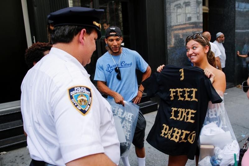 A shopper shows her u00e2u20acu02dcThe Life of Pablou00e2u20acu2122 merchandise to NYPD officers after visiting a pop up store featuring fashion by Kanye West in Manhattan, New York, August 19, 2016. u00e2u20acu2022 Reuters pic