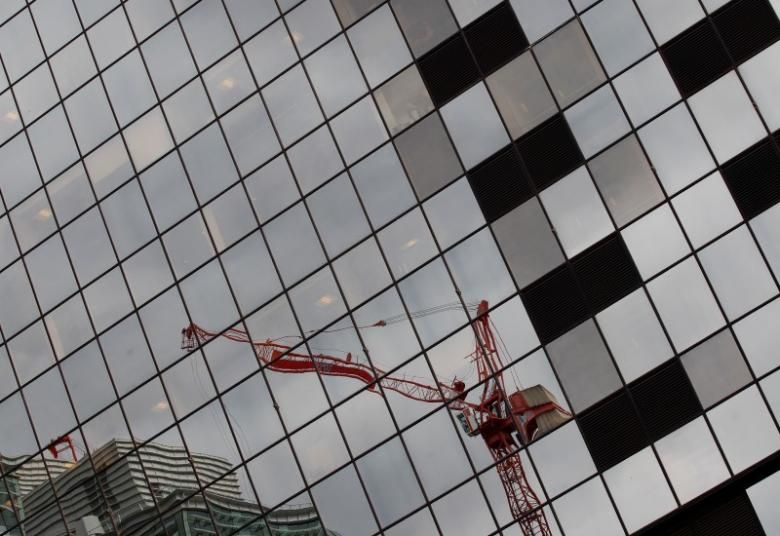 A crane on a construction site is reflected in office windows in Birmingham, central England, in this July 26, 2011 file photo. REUTERS/Darren Staples