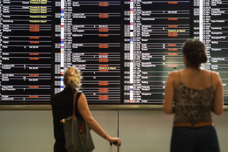 Passengers look at an information board displaying a list of cancelled and delayed flights in Hong Kong on August 1, 2016, shortly after a 'T8' storm signal was raised for Typhoon Nida. u00e2u20acu201d AFP pic