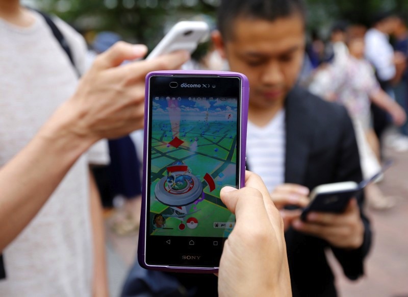 Men play the augmented reality mobile game 'Pokemon Go' by Nintendo on their mobile phone near a busy crossing in Shibuya district in Tokyo, Japan, July 22, 2016. u00e2u20acu201d Reuters pic