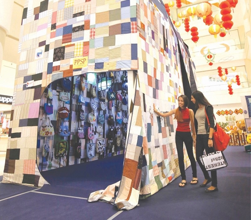 Visitors admire handbags in the worldu00e2u20acu2122s largest holdall bag displayed at the Ipoh Parade mall on February 19.